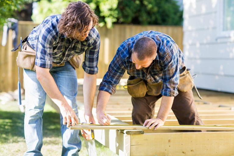 man and woman measuring wood to prepare mobile home for hurricane
