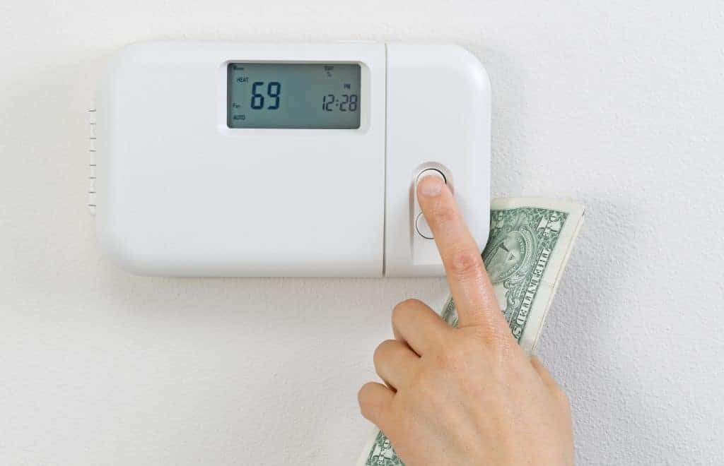 A hand changing the temperature on the thermostat.