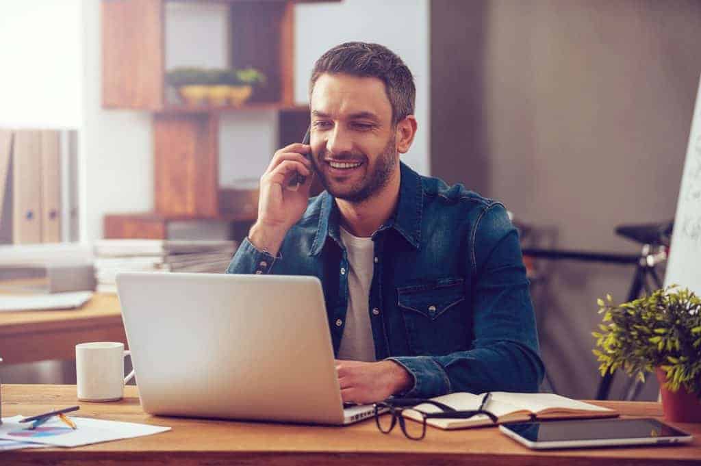 man on phone and laptop buying a mobile home for an investment opportunity