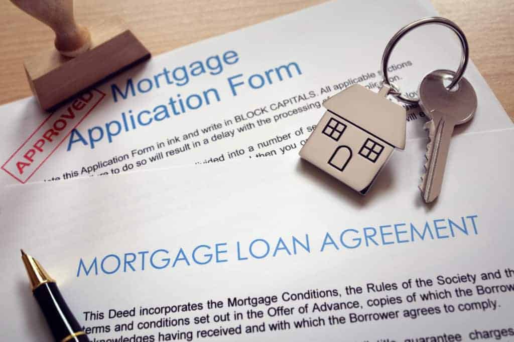 Approved Mortgage loan agreement application with key on house shaped keyring