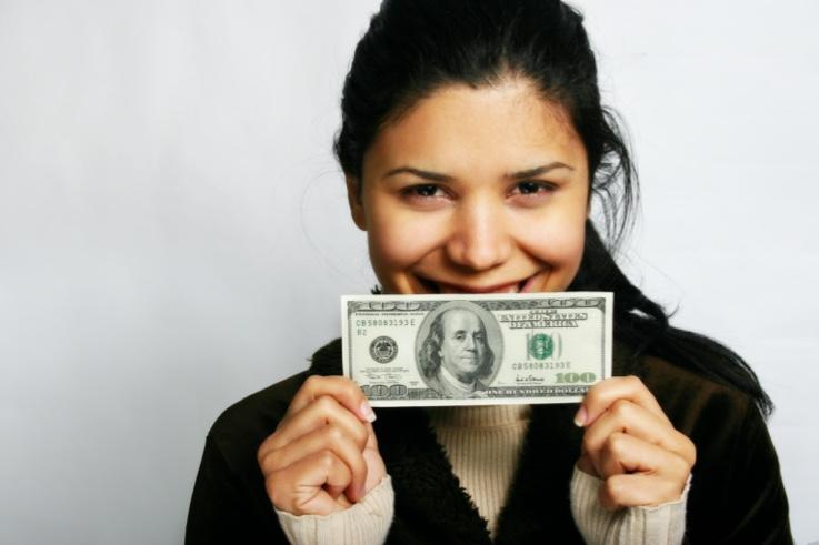 Woman smiling and holding 100 dollar bill