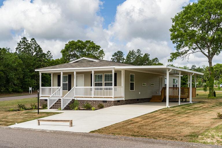 Clean and tidy mobile home with attached carport and paved driveway