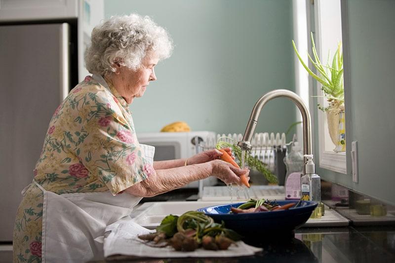 elderly woman washing vegatables in home