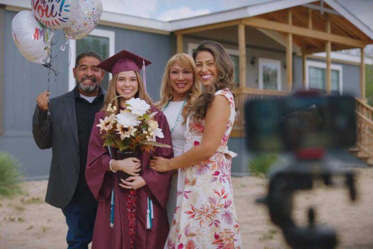 Family taking a graduation photo in front of a new mobile home.